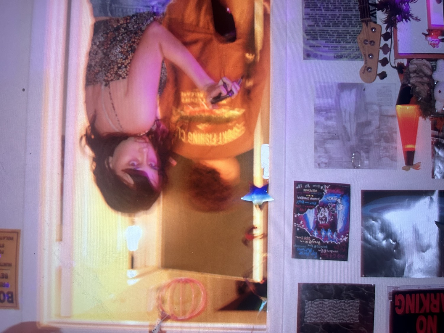Bedroom wall covered in show posters, a bass guitar and a lava lamp